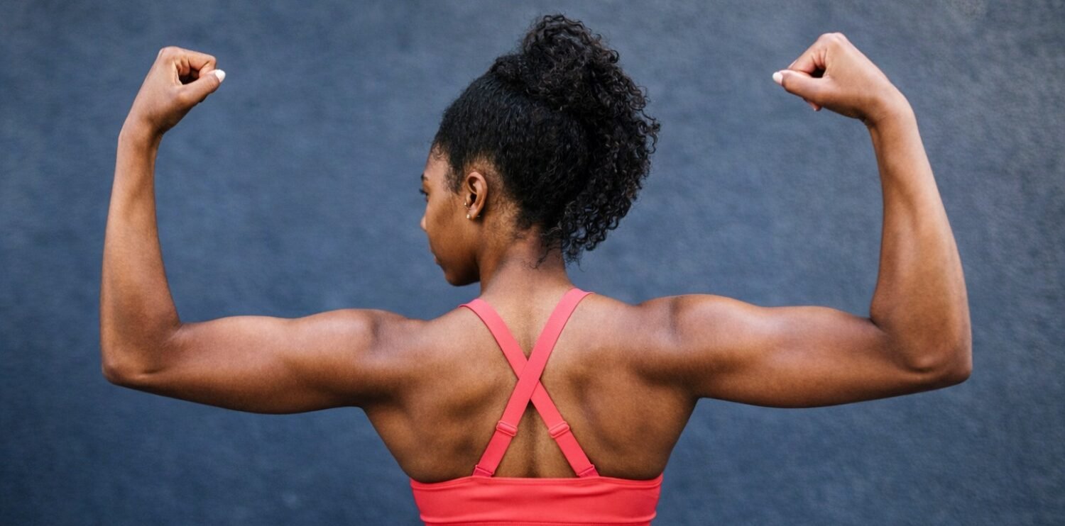 a women in a pink top flexing her muscles