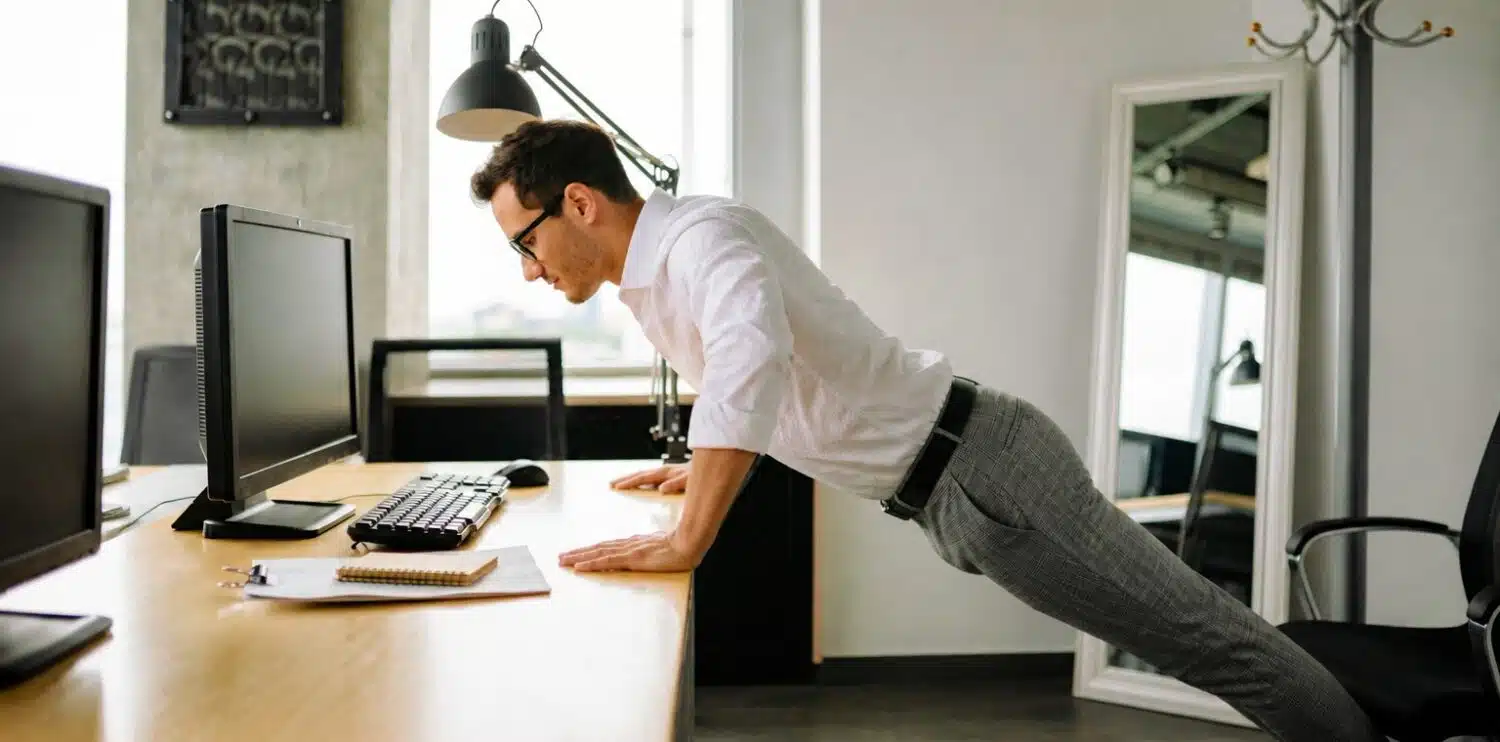 a man doing press ups against a desk in the office
