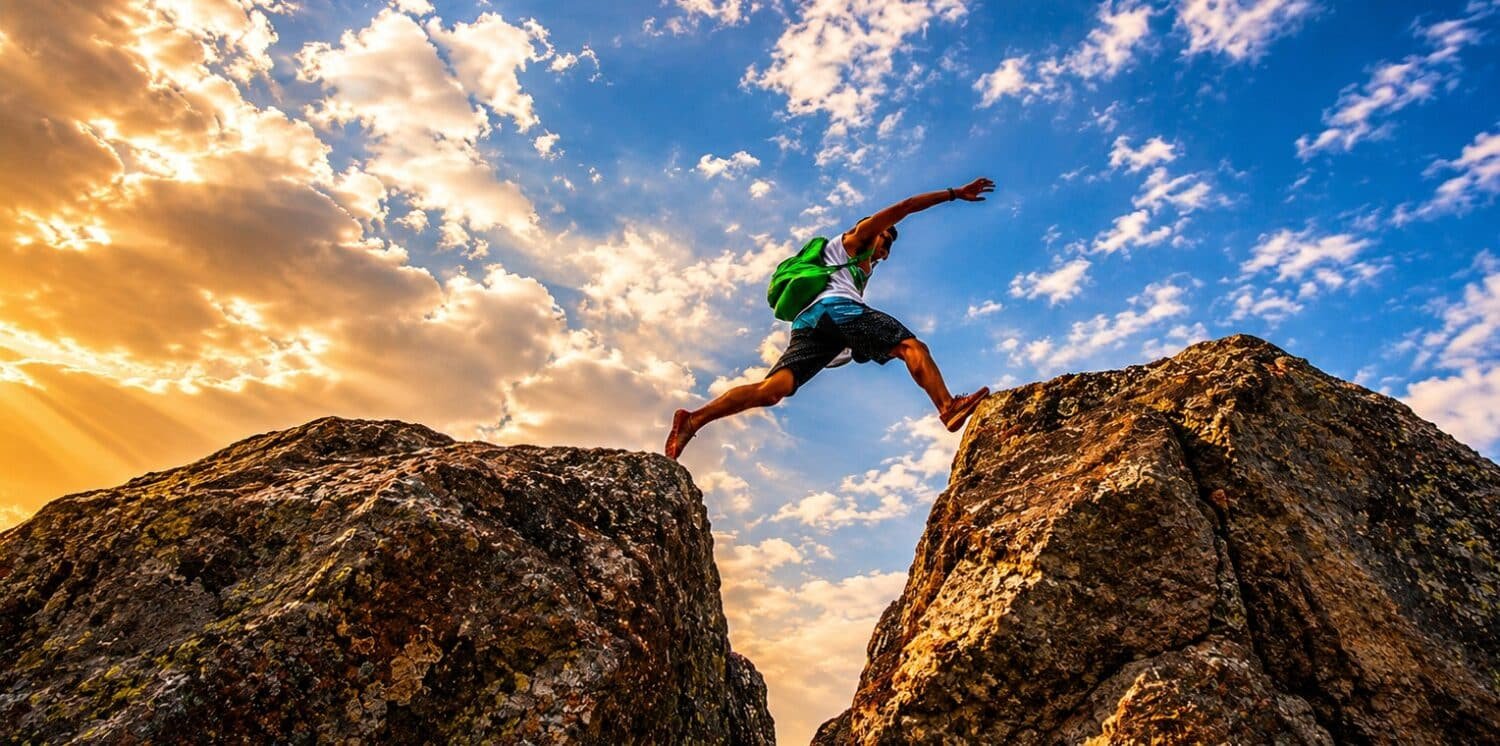 man leaping across a gap in the rocks