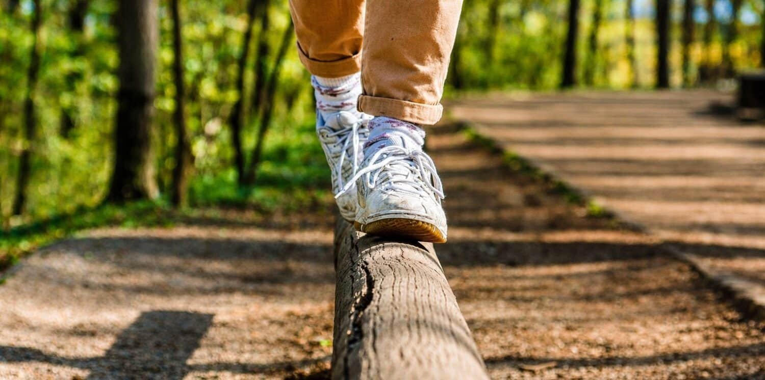 person balancing on a woodland beam